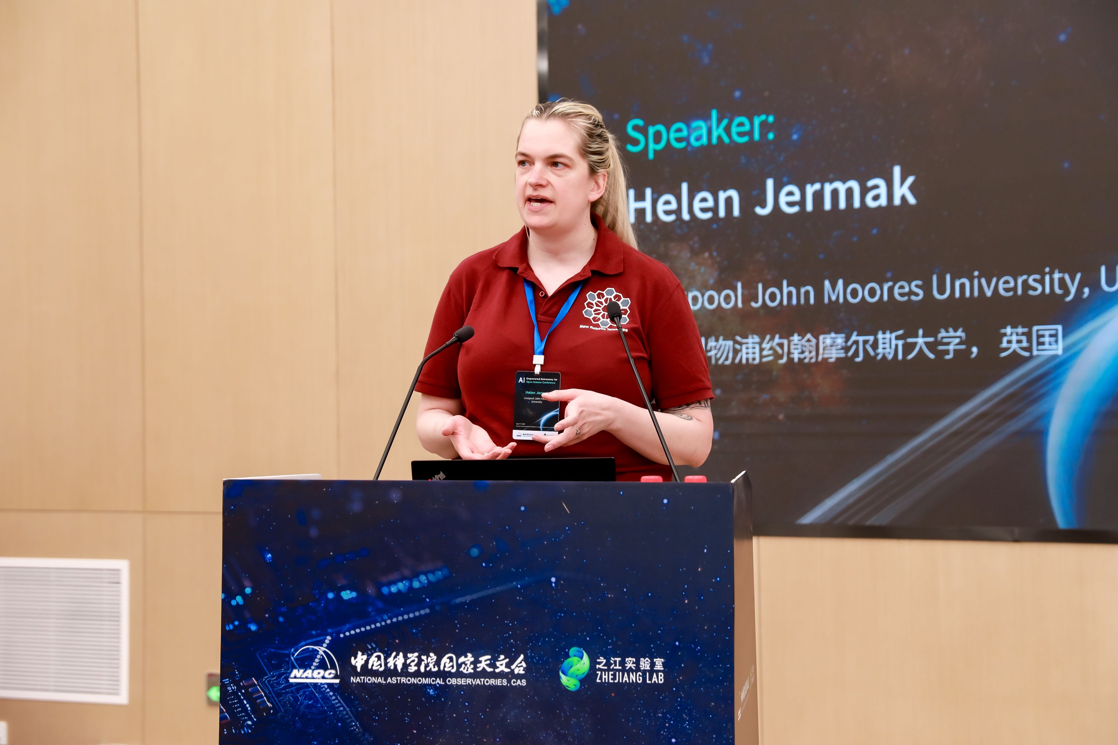 Helen speaking on the stage at the conference wearing an NRT t-shirt